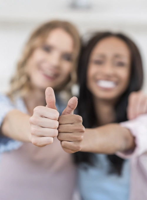 Chiropractic Bastrop TX Contact us row Two women with their arms stretched out making a thumbs-up sign