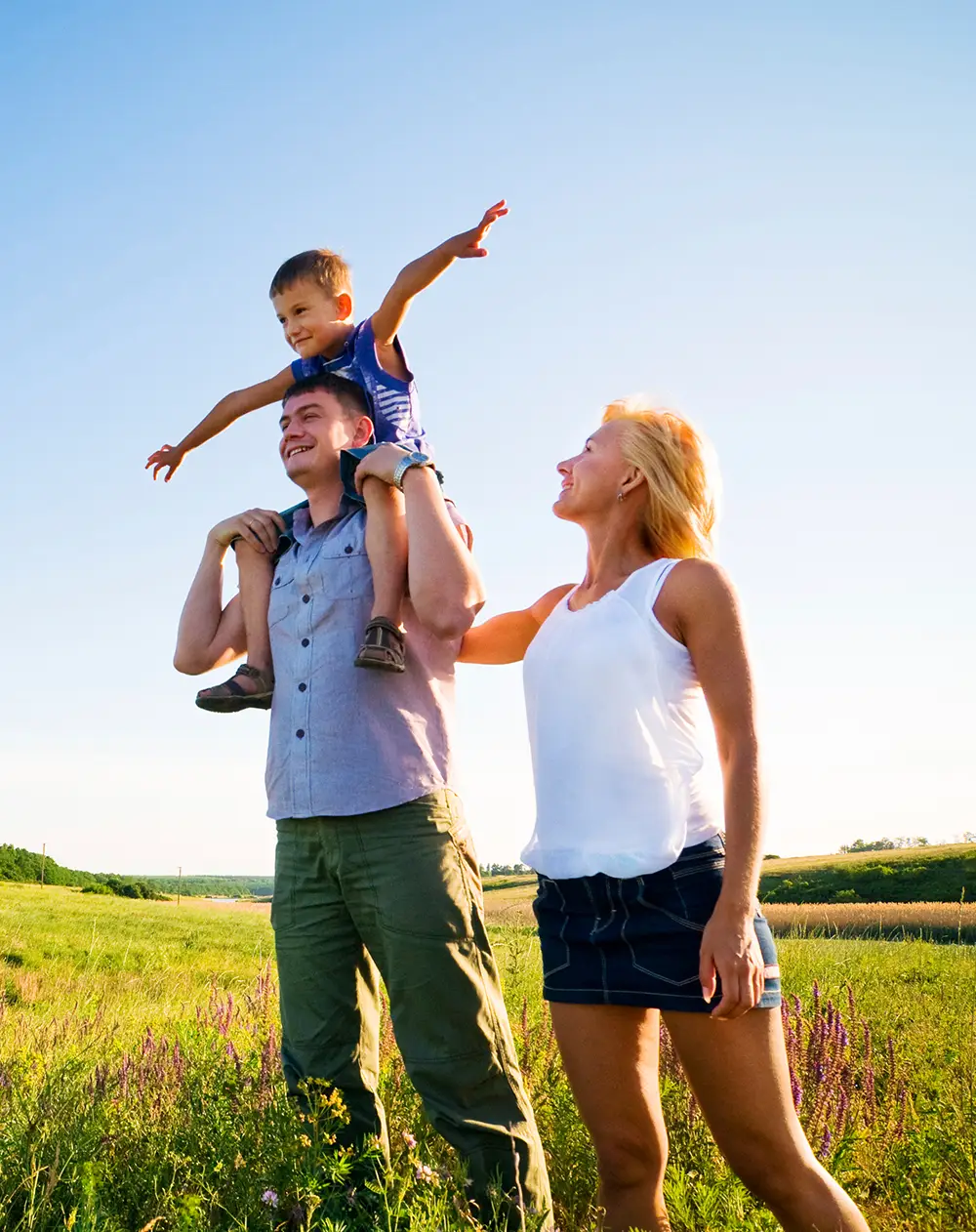 Chiropractic-Bastrop TX HP Hero A dad carrying his son on his shoulders, happily walking with the mom in the park